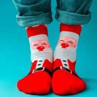 male legs in red Christmas funny socks on a blue background
